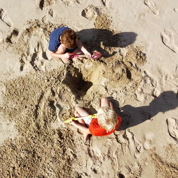 2 мальчика лежат на песке днем онлайн-пазл