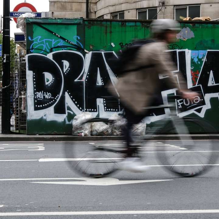 мъж в кафяво яке, каращ велосипед по пътя през деня онлайн пъзел