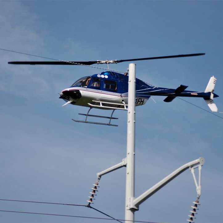 helicóptero blanco y azul volando bajo un cielo azul puzzle deslizante online