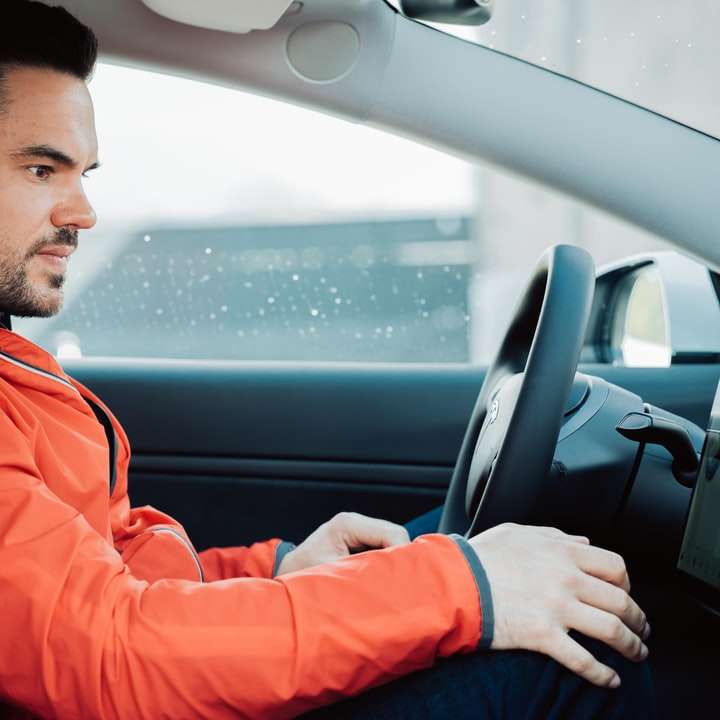 человек в красной куртке за рулем автомобиля онлайн-пазл