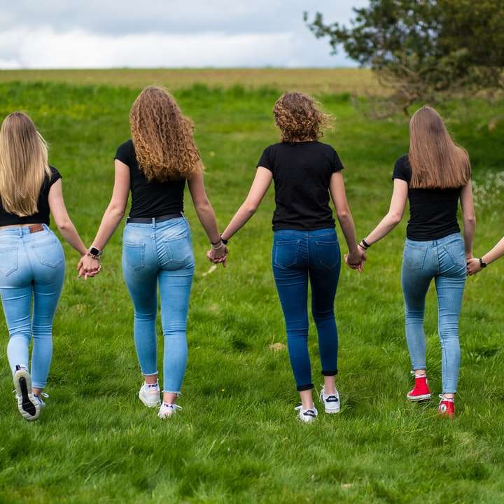 3 mulheres em pé no campo de grama verde durante o dia puzzle online