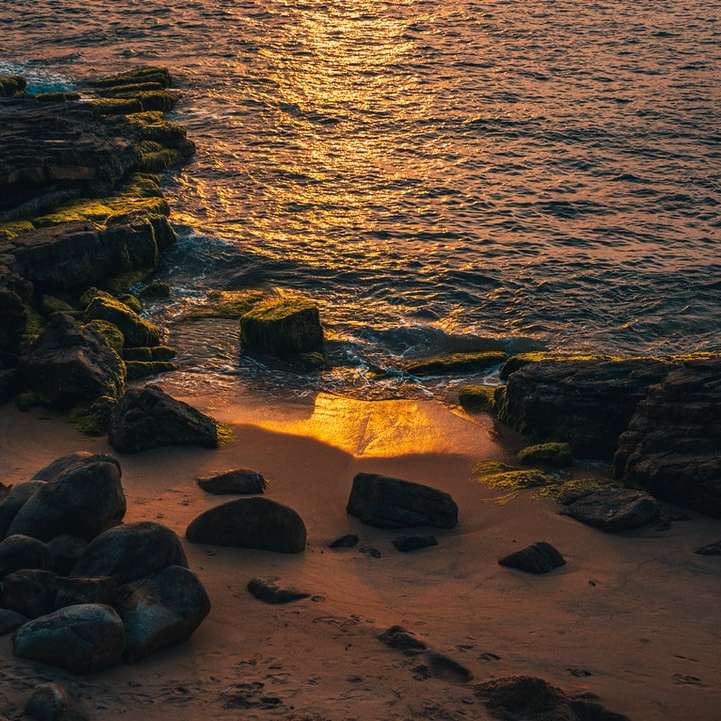 rochas marrons na costa do mar durante o pôr do sol puzzle deslizante online