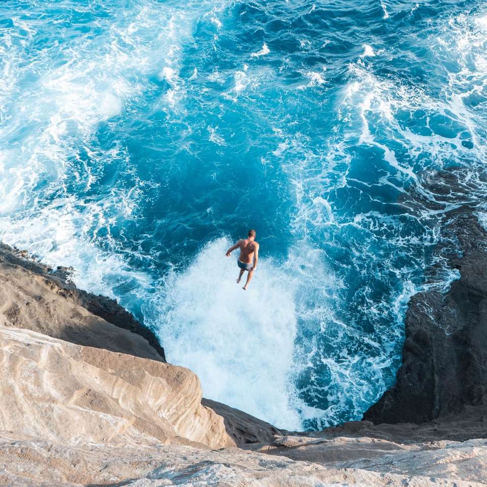 Luftbild eines Mannes, der auf einer Klippe ins Wasser springt Online-Puzzle