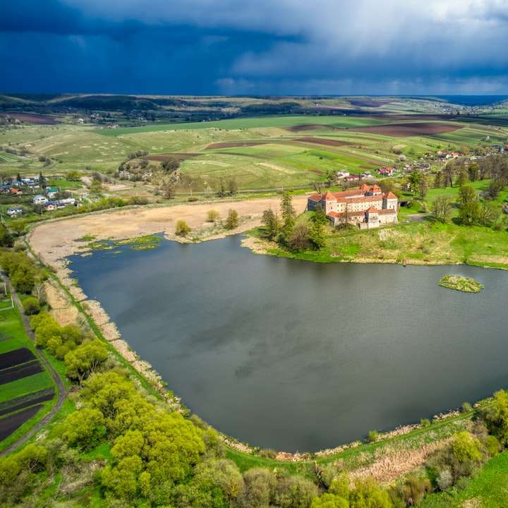 luchtfoto van groen grasveld in de buurt van meer overdag online puzzel