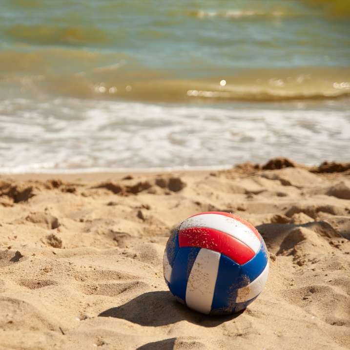 vit röd och blå beachvolleyboll på stranden under dagtid Pussel online