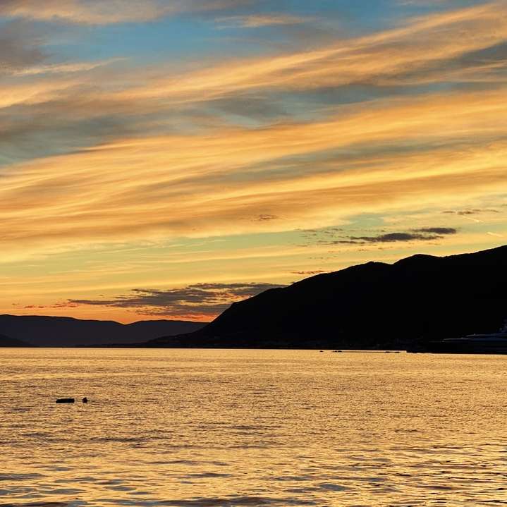 silhouet van berg naast zee tijdens zonsondergang online puzzel