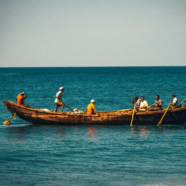 άνθρωποι που ιππεύουν σε καφέ βάρκα στη θάλασσα κατά τη διάρκεια της ημέρας συρόμενο παζλ online