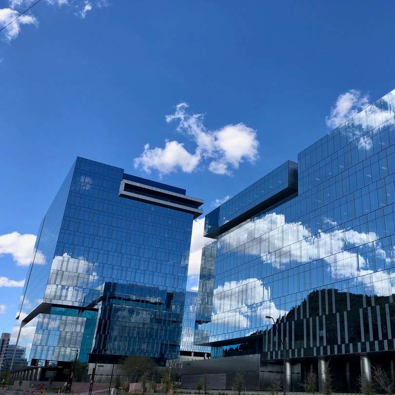 blauw en wit glazen gebouw overdag onder de blauwe lucht online puzzel