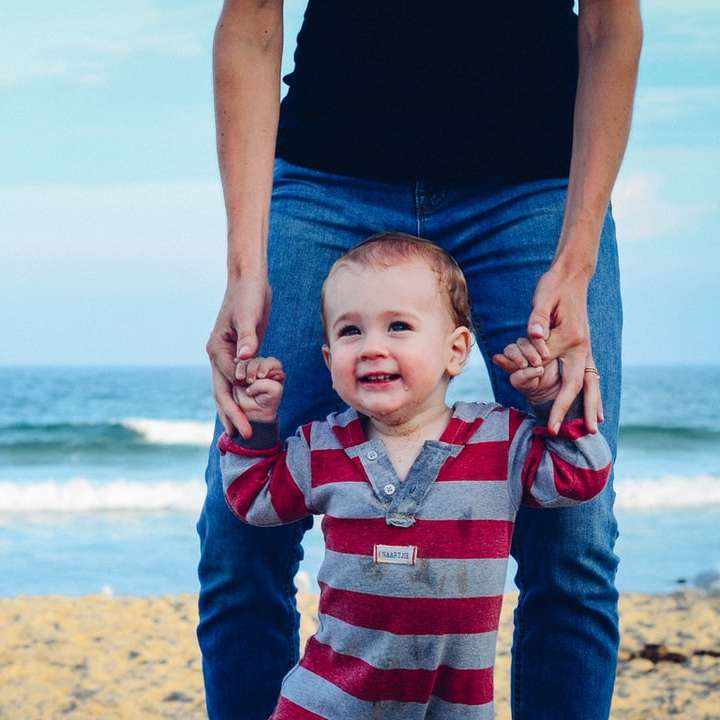 Mann hilft Baby am Strand zu laufen Schiebepuzzle online
