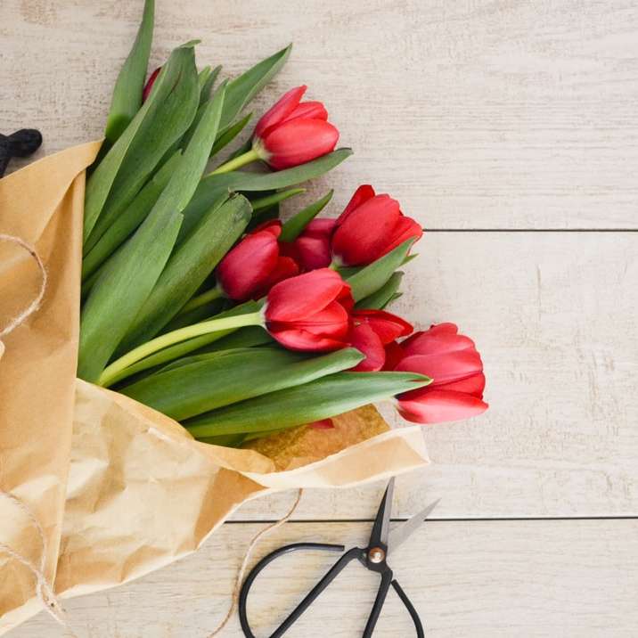 Ramo de flores de tulipán rojo sobre palet de madera marrón rompecabezas en línea