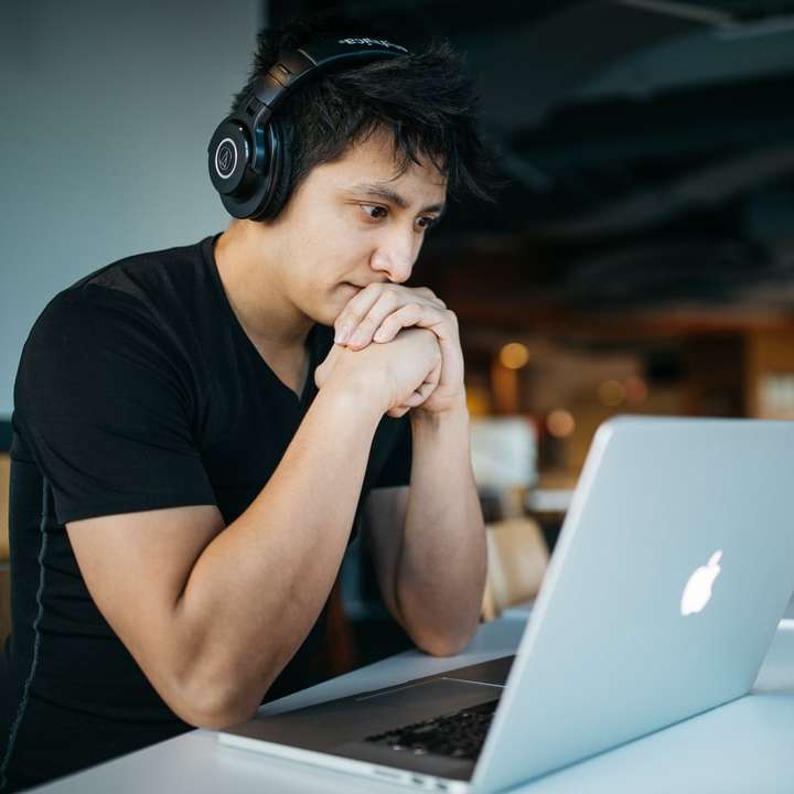 Mann mit Kopfhörern, während er auf einem Stuhl davor sitzt Schiebepuzzle online