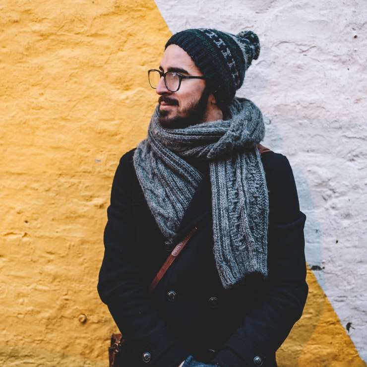 Человек в черном пальто с серым шарфом стоит впереди онлайн-пазл