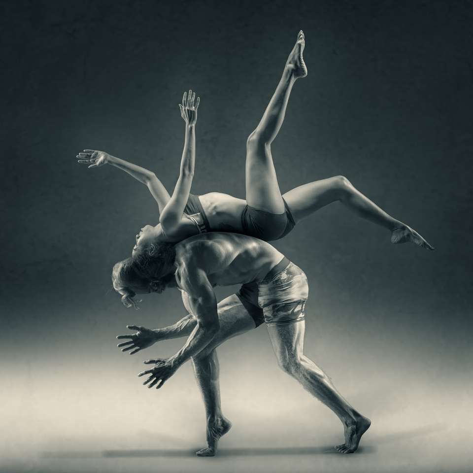 A woman flipping over a man, back to back. online puzzle