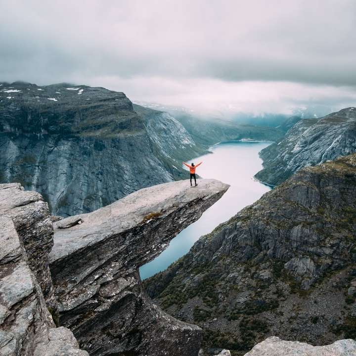 osoba stojąca na szarej formacji skalnej wysokościowej w ciągu dnia puzzle przesuwne online