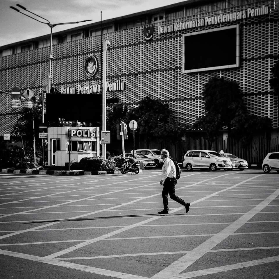 photo en niveaux de gris d'un homme marchant à côté d'un bâtiment puzzle en ligne