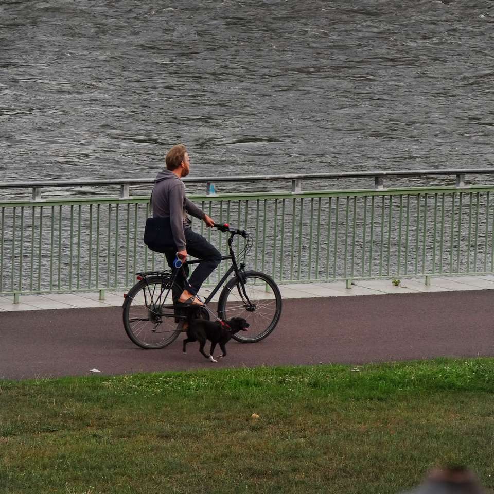 человек в коричневой куртке катается на черном велосипеде онлайн-пазл