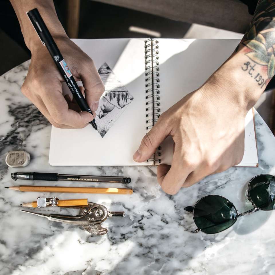 pessoa desenhando no caderno usando caneta puzzle deslizante online