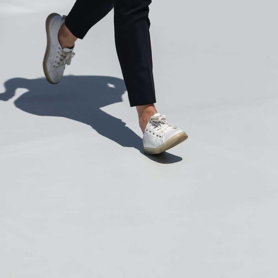 person i svarta byxor och vita sneakers glidande pussel online