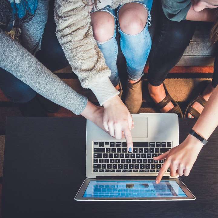 Drei Personen, die auf den silbernen Laptop zeigen Online-Puzzle
