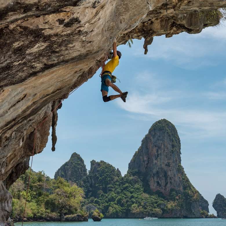 mężczyzna wspinający się na klif przy plaży puzzle online