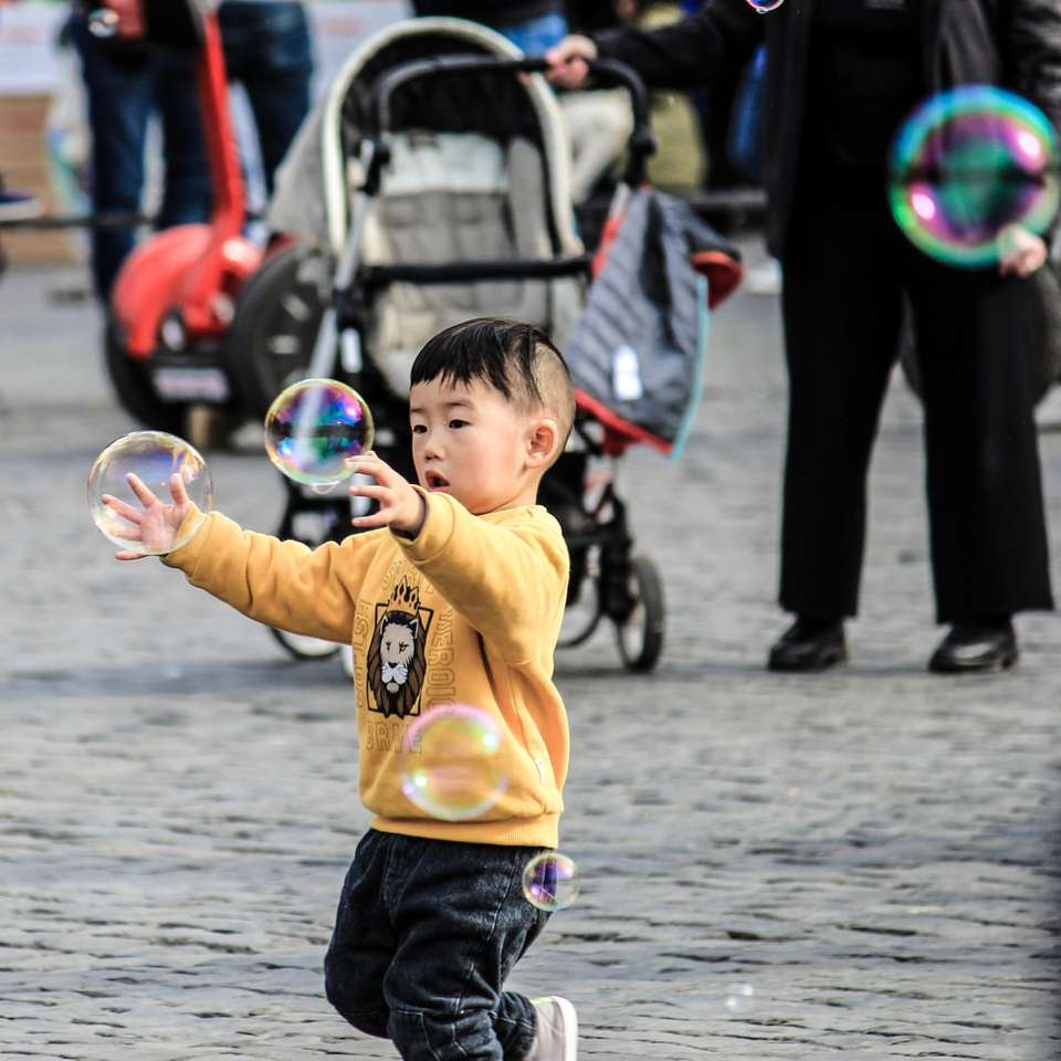 мальчик в желтом свитере играет с пузырями онлайн-пазл
