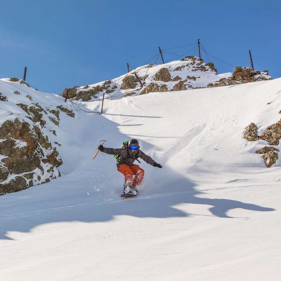 Mann in roter Jacke und schwarzer Hose beim Snowboardfahren Schiebepuzzle online