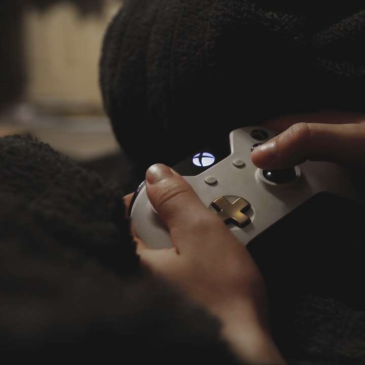 osoba trzymająca biały kontroler gier Xbox puzzle przesuwne online