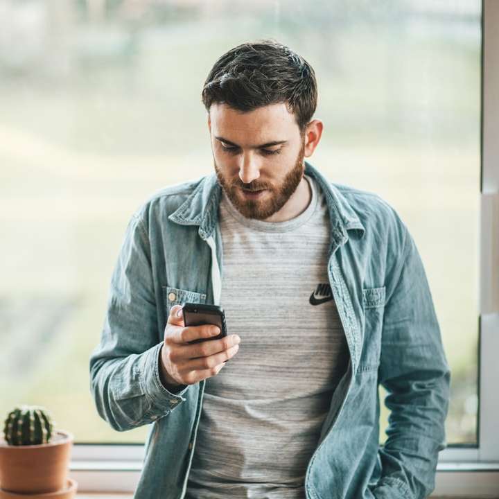 bărbat care ține un smartphone lângă fereastră alunecare puzzle online