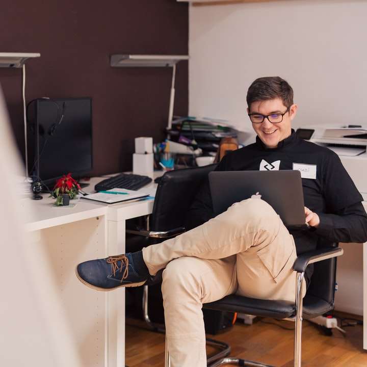 άνδρας που χαμογελά ενώ κάθεται και χρησιμοποιεί MacBook συρόμενο παζλ online