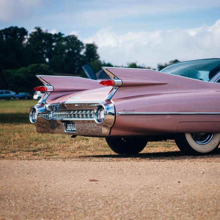 vintage roze muscle car geparkeerd in de buurt van grasveld schuifpuzzel online