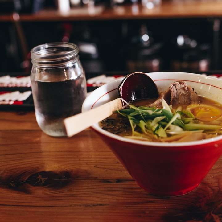 soppa med grönsaker bredvid ätpinnar och ett glas vatten Pussel online