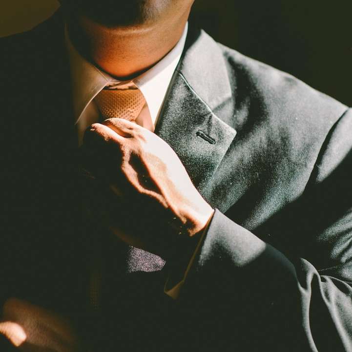 Ein Mann im schwarzen Anzug lockert seine Krawatte Schiebepuzzle online