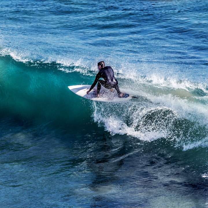 Person auf weißem Surfbrett, umgeben von blauem Meerwasser Schiebepuzzle online
