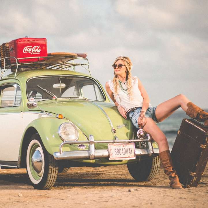 žena opírající se o zelené a bílé Volkswagen Beetle poblíž moře online puzzle