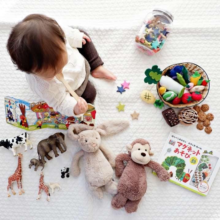 chłopiec siedzący na białym obrusie otoczony zabawkami puzzle online