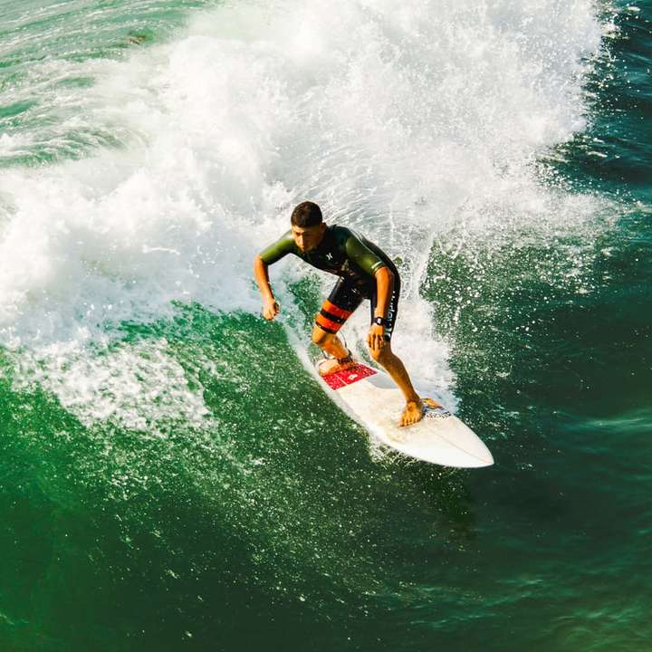 Mann auf Surfbrett gegen Wellen surfen Online-Puzzle