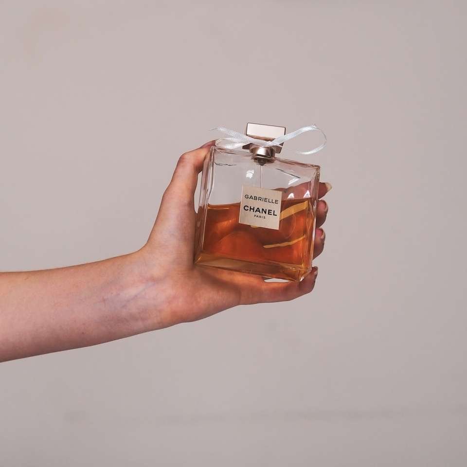 osoba trzymająca przezroczystą szklaną butelkę perfum puzzle online
