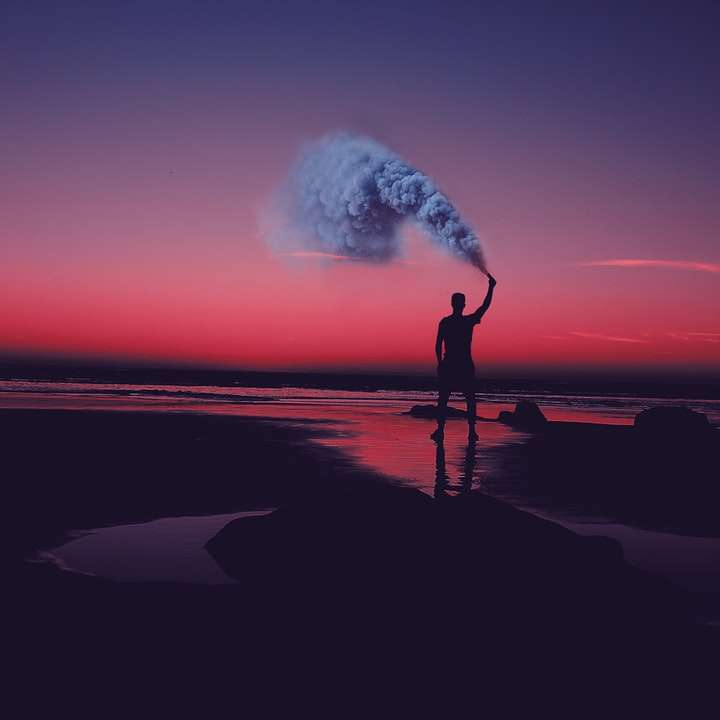 silhouette d'homme debout sur le bord de mer tenant une canette de fumée puzzle coulissant en ligne