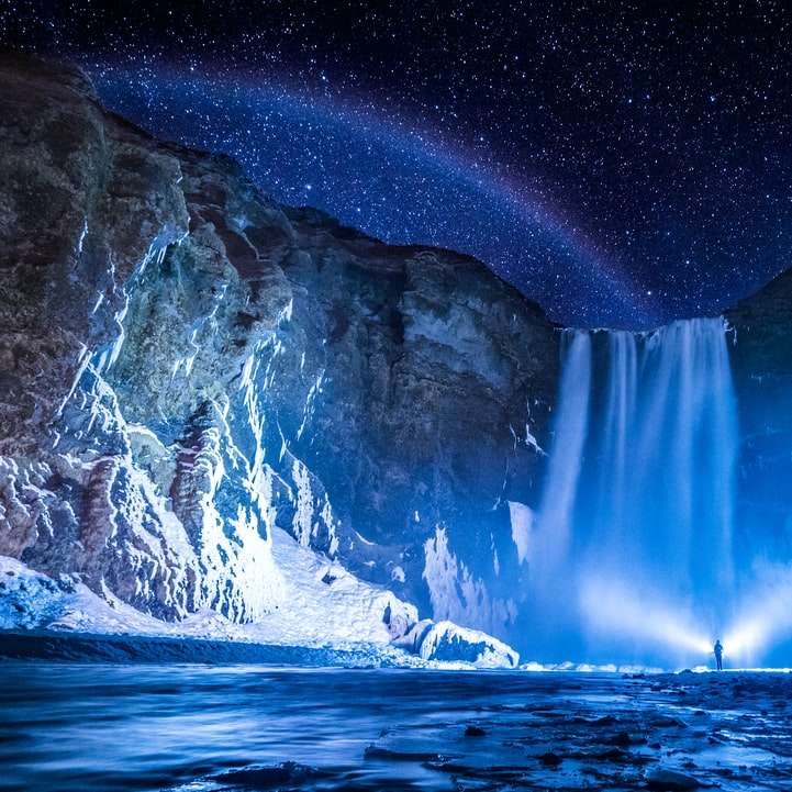 Person vor Wasserfällen während der Nacht Schiebepuzzle online