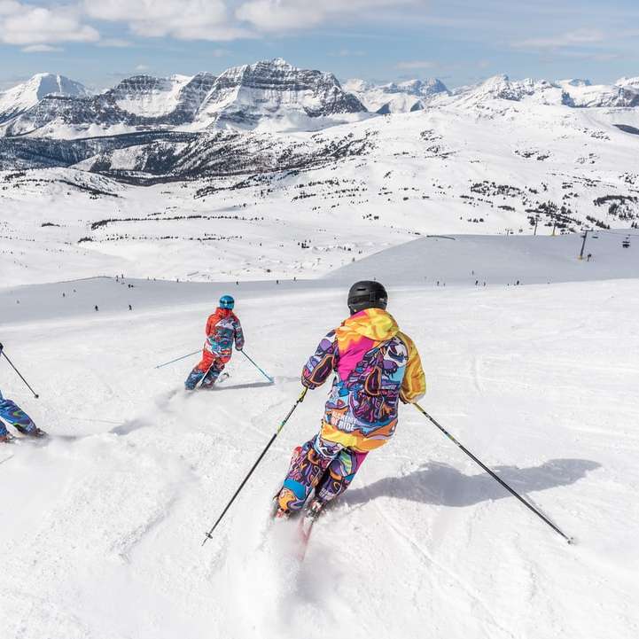 2 personas con chaqueta amarilla y casco azul montando cuchillas de esquí rompecabezas en línea