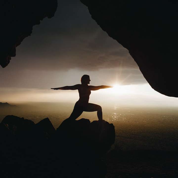 silhouette de personne en poste de yoga au sommet de la falaise puzzle en ligne