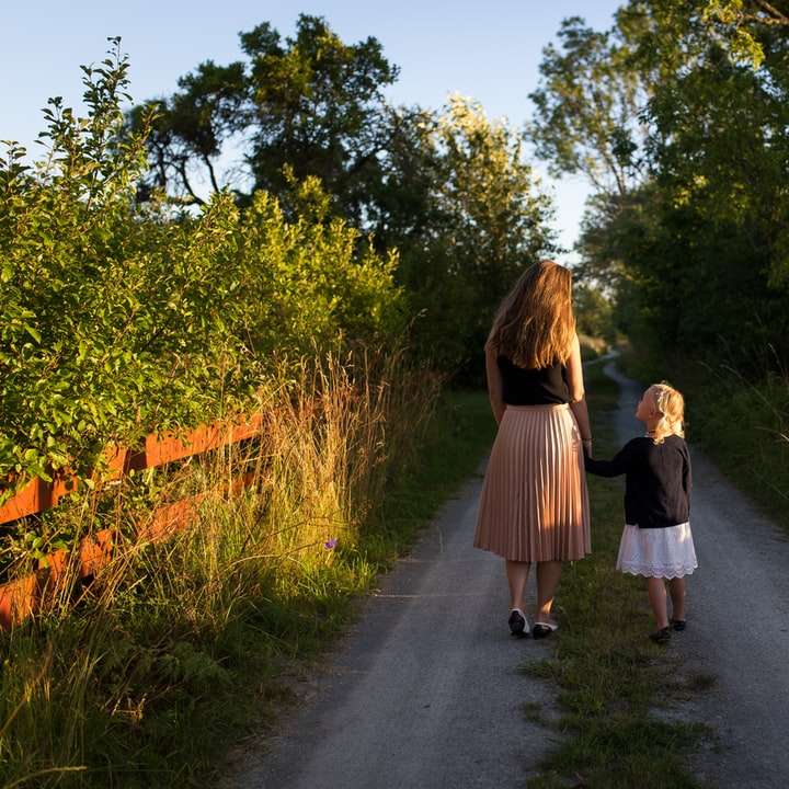 woman and girl walking on road surrounded by green grass online puzzle