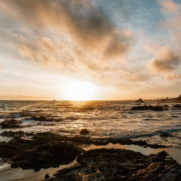 Olas del océano rompiendo contra las rocas durante la puesta de sol puzzle deslizante online