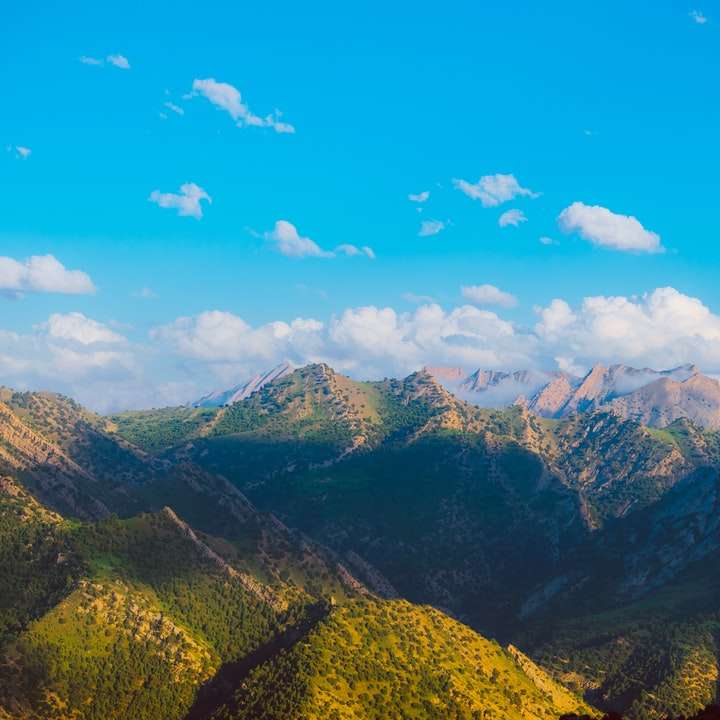 zelené a hnědé hory pod modrou oblohou během dne posuvné puzzle online