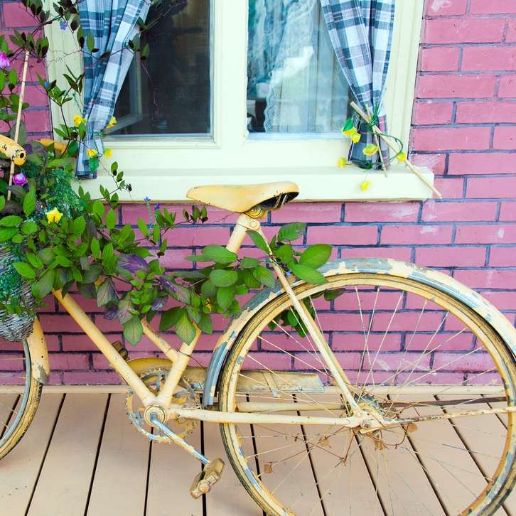 Bicicleta de ciudad marrón con flores cerca del edificio de ladrillo rojo rompecabezas en línea