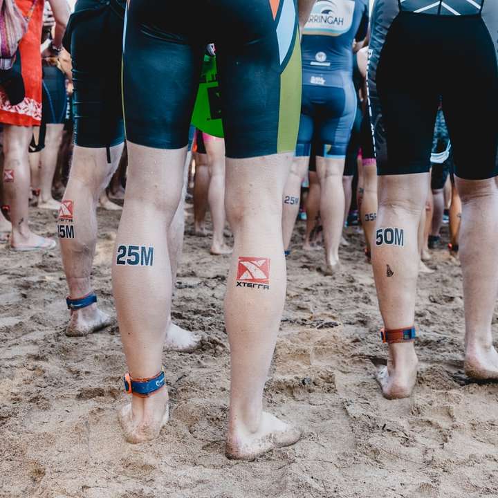 pessoas em shorts azul e vermelho em pé na areia marrom puzzle online
