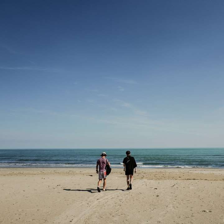 двама души, стоящи близо до морския бряг плъзгащ се пъзел онлайн