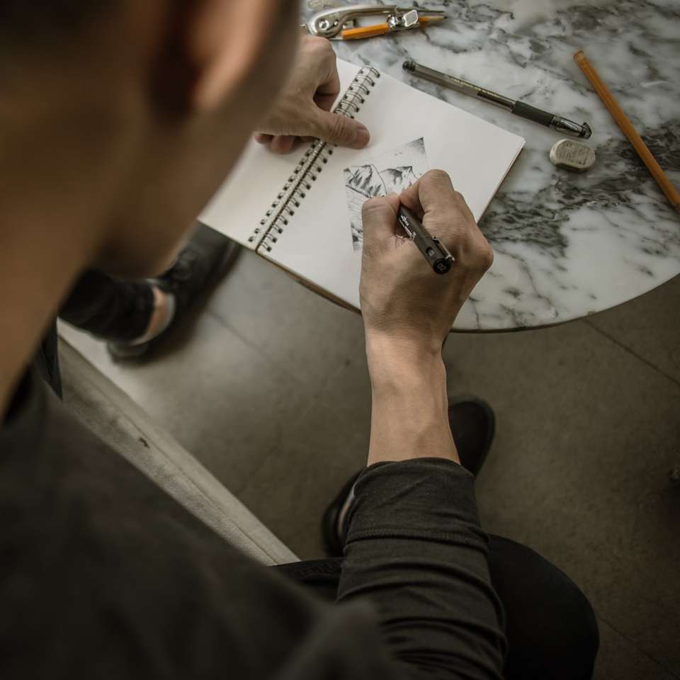 mężczyzna rysujący górę na białym notebooku puzzle przesuwne online