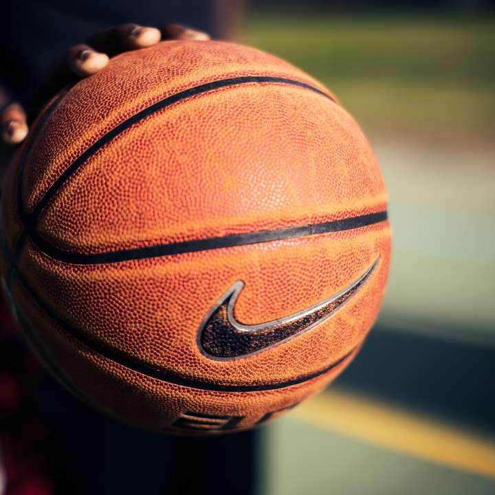 човек, който държи кафява баскетболна топка Nike онлайн пъзел