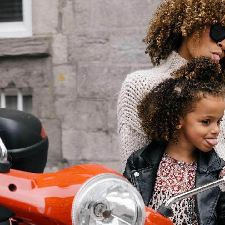 mujer y niña mostrando sus lenguas al lado de la motocicleta puzzle deslizante online